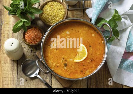 Cucina turca. Zuppa tradizionale con riso, lenticchie e menta su un tavolo rustico Foto Stock