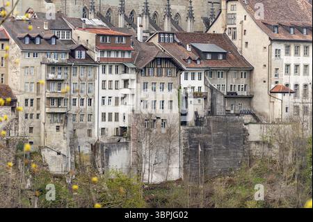Edifici residenziali storici a più piani densamente pieni, con finestre e balconi sul bordo di una scogliera nella città vecchia di Friburgo, in Svizzera Foto Stock