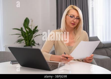 Psicologo professionista biondo che prende appunti e utilizza il laptop. Foto Stock