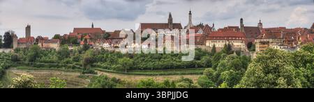 Vista panoramica dello skyline della storica città vecchia di Rothenburg ob der Tauber con le sue vecchie torri, le mura della città e le case con il tempo nuvoloso, RO Foto Stock
