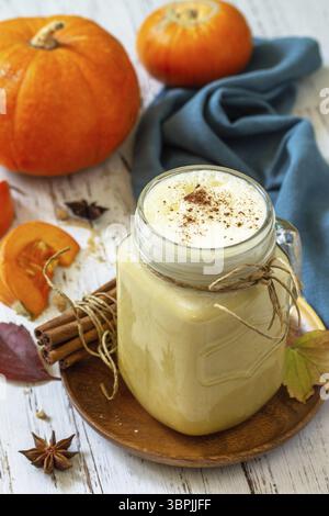 Drink autunnale. Latte speziato di zucca o caffè in vetro su un rustico tavolo di legno Foto Stock