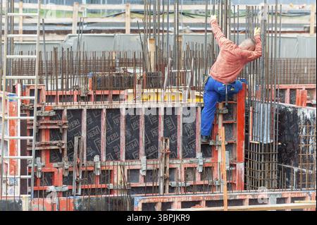 Un operaio edile in un grande cantiere si arrampica su una cassaforma per cemento armato, Francoforte sul meno, Germania, Europa Foto Stock