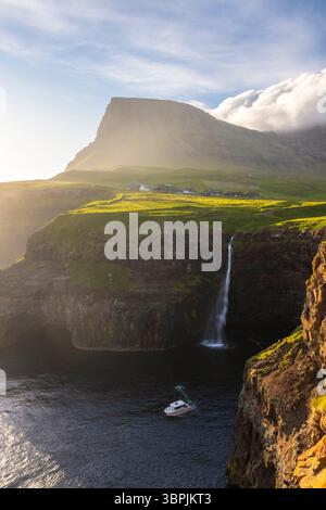 Vista della cascata Mulafossur con il piccolo villaggio di Gasadalur. Isola di Vagar, Isole Faroe, Danimarca, Europa. Foto Stock