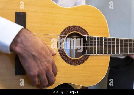 Primo piano di un chitarrista classico che tiene la chitarra spagnola da vicino in studio Foto Stock