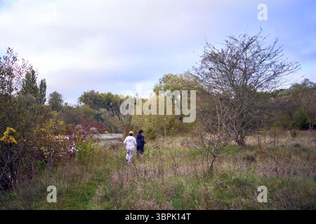 la donna di mezza età e la sua vecchia madre fanno jogging mattutino insieme per mantenere la salute vicino al fiume in autunno Foto Stock