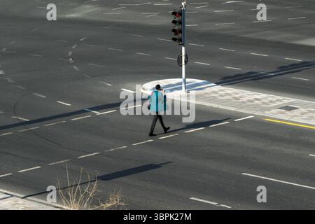 Dall'alto di giovani uomini che attraversano la strada. Attraversamento pedonale della strada in città, vista dall'alto Foto Stock