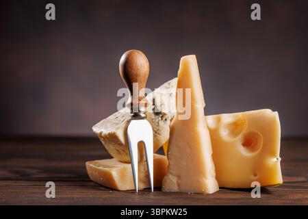 Formaggi assortiti di forme e consistenze diverse, esposti insieme su una superficie rustica Foto Stock