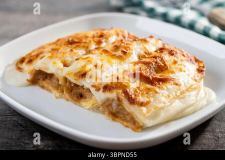 Cannelloni al forno con formaggio e salsa bechamel su tavola di legno Foto Stock
