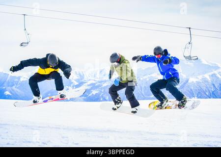 Tre amici snowboarder nella stazione sciistica in vacanza sulla neve. Concetto di riscaldamento in giornata fredda coperto, allenamento, divertimento, esercizio fisico, sport Sn Foto Stock