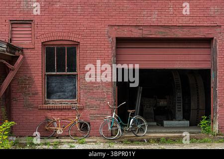 Due biciclette appoggiate su un vecchio edificio in mattoni abbandonato, Indiana USA Foto Stock