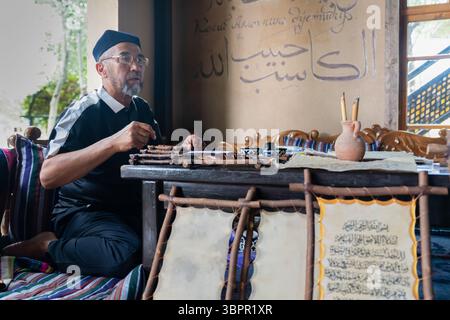 Samarcanda, Uzbekistan - 28 maggio 2025: Artista che esegue calligrafia in arabo Foto Stock