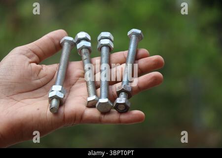 Bullone lungo con dadi in metallo tenuti in mano. Dado metallico e bulloni lunghi chiamati anche dispositivi di fissaggio Foto Stock