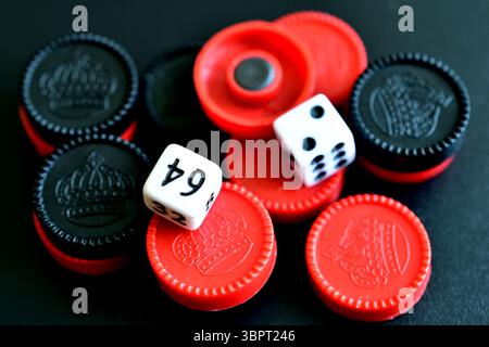 Gioco da tavolo. Le pedine e i dadi neri e rossi si trovano su uno sfondo nero. Foto Stock