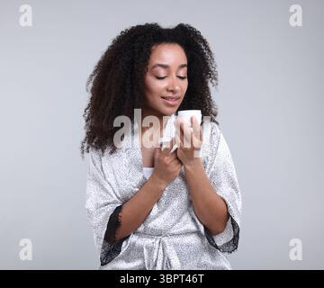 Bella donna brasiliana con barattolo di crema di collagene su sfondo grigio Foto Stock