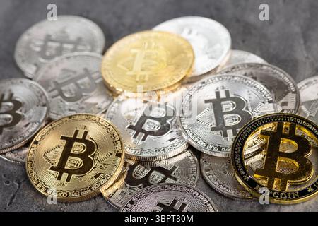 Una disposizione di monete Bitcoin d'oro e d'argento poste su una superficie di pietra testurizzata, simboleggiando concetti di criptovaluta e valuta digitale. Foto Stock