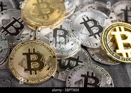 Una disposizione di monete Bitcoin d'oro e d'argento poste su una superficie di pietra testurizzata, simboleggiando concetti di criptovaluta e valuta digitale. Foto Stock