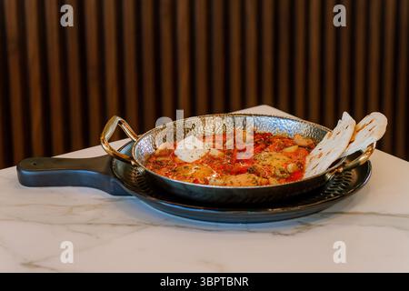 Piatto shakshuka con uova, salsa di pomodoro e pane pita Foto Stock