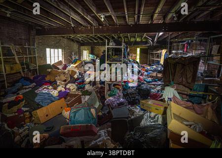 Camera piena di vestiti sporchi nell'edificio abbandonato, Indiana, USA Foto Stock