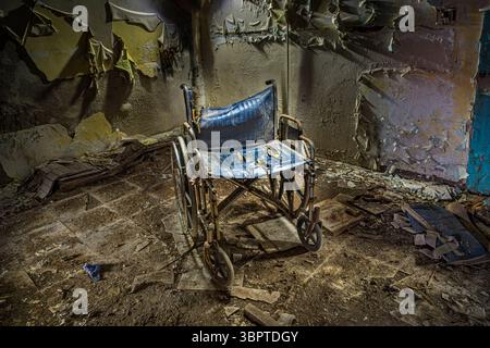 Sedia a rotelle solitaria in ospedale abbandonato, Indiana USA Foto Stock