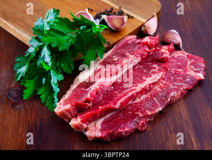 Carne di manzo marmorizzata a fette crude con prezzemolo e condimenti Foto Stock