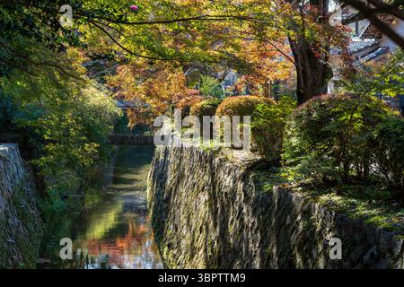 Il tranquillo sentiero dei filosofi (Tetsugaku no michi) a Kyoto, una passerella in pietra lungo un canale fiancheggiato da fogliame autunnale. Sakyo-ku, Kyoto, Giappone. Foto Stock
