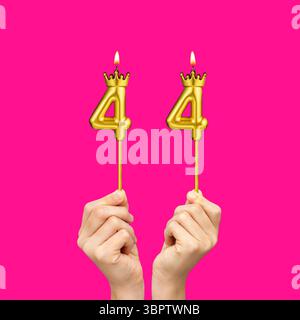 Mani che tengono candele a forma di numero - compleanno numero 44 Foto Stock