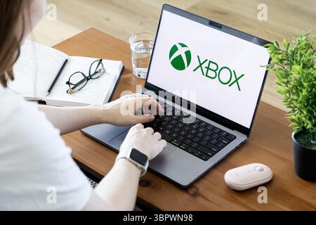 Poznan, Polonia - 15 giugno 2025: Logo del marchio Xbox visualizzato sullo schermo del laptop, digitazione delle mani della persona, esplorazione attiva dei contenuti di gioco, entertai digitale Foto Stock