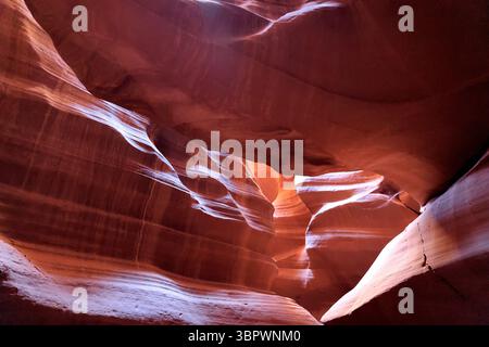 La luce soffusa rivela le curve lisce delle pareti in pietra arenaria dell'Antelope Canyon a Page Arizona, evidenziando texture vorticose modellate dall'antico flusso d'acqua. Foto Stock