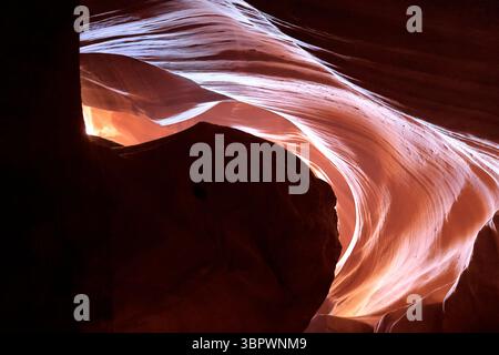 La luce filtra attraverso le alte pareti dell'Antelope Canyon in Arizona, tracciando morbide curve di arenaria scolpita dal vento e dipingendo onde di colore attraverso la roccia Foto Stock
