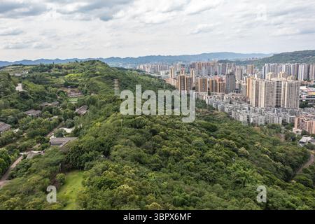 (250710) -- CHONGQING, 10 luglio 2025 (Xinhua) -- questa foto aerea del drone scattata il 3 luglio 2025 mostra la vista di un parco nel distretto di Jiangjin, nel comune di Chongqing della Cina sud-occidentale. Jiangjin si trova in un punto strategico lungo il fiume Yangtze. Gli edifici cittadini sono stati costruiti lungo le pendici sulle rive del fiume. Da lontano, sembrano una foresta che cresce dalle scogliere. Negli ultimi anni, Jiangjin ha promosso la gestione ecologica del fiume Yangtze. Il miglioramento della qualità dell'acqua ha attratto le specie ittiche rare a ritornare. (Xinhua/Huang Wei) Foto Stock