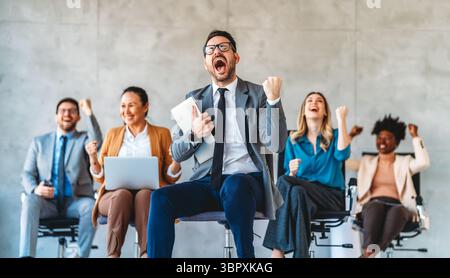 Entusiasta entusiasta, entusiasta e diversificata gente d'affari, il team festeggia la vittoria aziendale insieme in ufficio Foto Stock