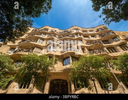 La facciata ondulata in pietra di Casa Milà, conosciuta anche come la Pedrera, di Antoni Gaudí a Barcellona. ripresa dal livello della strada guardando verso l'alto Foto Stock