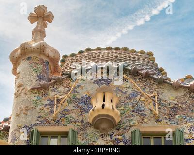 L'iconico tetto "dorso del Drago" di Casa Batlló, caratterizzato da piastrelle in ceramica colorata "scale" e una croce, disegnata da Gaudí, Barcellona, Spagna. Foto Stock
