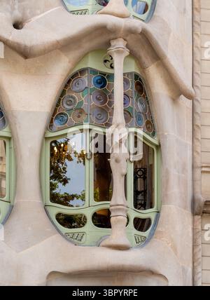 Un primo piano di una colonna "ossa" e una vetrata colorata al piano principale di Casa Batlló, un capolavoro di Antoni Gaudí a Barcellona, Spagna. Foto Stock