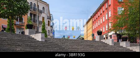 Sodertalje, Svezia - 6 giugno 2025: Una vivace scena di strada con edifici colorati su entrambi i lati e palloncini decorativi appesi sopra. L'avambraccio Foto Stock