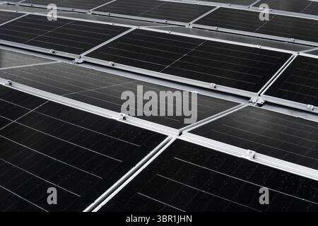 Pannelli solari su un tetto piatto a membrana, disposti da est a ovest per una generazione di energia bilanciata durante tutto il giorno. Foto Stock