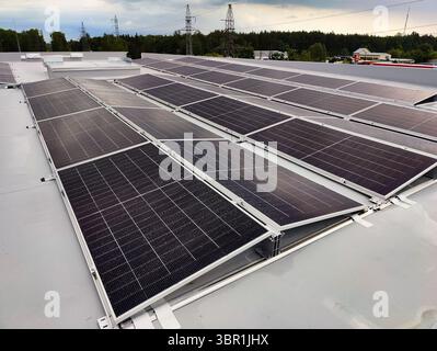 Pannelli solari su un tetto piatto a membrana, disposti da est a ovest per una generazione di energia bilanciata durante tutto il giorno. Foto Stock
