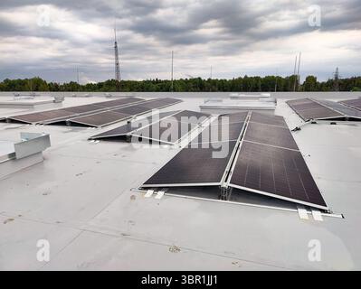 Pannelli solari su un tetto piatto a membrana, disposti da est a ovest per una generazione di energia bilanciata durante tutto il giorno. Foto Stock