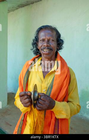 Il musicista itinerante suona il piatto mentre si reca per eseguire il rituale indù in un villaggio tribale di Bhatra, Pupujain, Orissa, India, Asia. Foto Stock