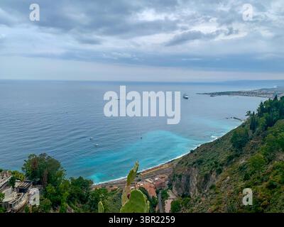 Dalla cima di Piazza IX aprile a Taormina, si apre una vista panoramica mozzafiato - acque blu vivide del Mar Ionio sotto un suggestivo skyline. Foto Stock