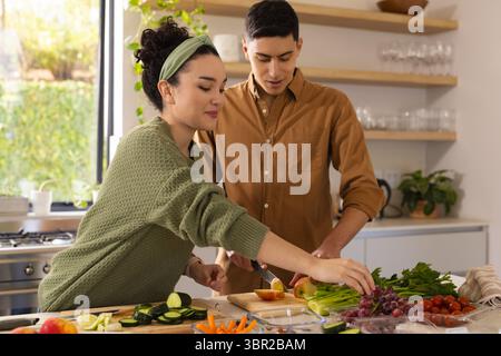 Accoppiare la mela affettata su un tagliere di legno e raggiungere l'uva nella luminosa cucina casalinga. Sano, culinario, rustico, stile di vita, freschezza, nazionale Foto Stock