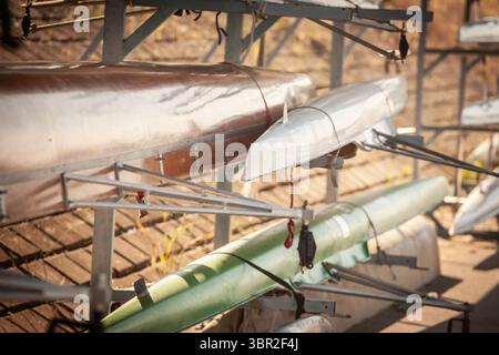 Vista superficiale delle conchiglie da corsa sovrapposte su un portabagagli, scafi metallici e in fibra di vetro per travolgere il reo e i quattro equipaggi, luce solare mattutina catc Foto Stock