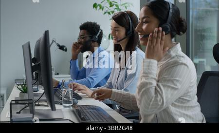 CallCenter aiuta gli agenti a contattare il call center persone multietniche donne indiane caucasiche felici in cuffia uomo africano che consulta il cliente Foto Stock