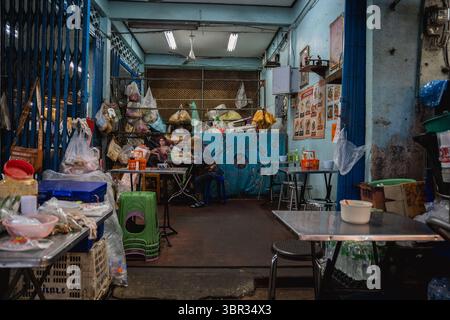 Bangkok, Thailandia. 11 luglio 2025. Una donna si vede mangiare in un piccolo negozio di alimentari. Ogni mattina a Bangkok, i monaci buddisti camminano per le strade per ricevere elemosine, offerte di cibo e fiori, dalla comunità laica. Nelle vicinanze, al mercato dei fiori di Yodpiman, i fiori vengono preparati e venduti per l'uso in questi rituali quotidiani radicati nella tradizione buddista Theravada. (Foto di Ploy Phutpheng/SOPA Images/Sipa USA) credito: SIPA USA/Alamy Live News Foto Stock