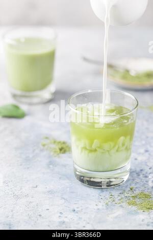Latte verde Matcha ghiacciato in bicchieri con polvere matcha su sfondo chiaro Foto Stock