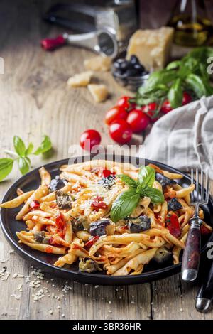Fusilli al ferro con salsa di pomodoro, pomodori, melanzane, cipolla e pepe su un piatto Foto Stock
