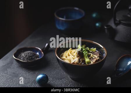 Asian spaghetti ramen zuppa con carne di manzo, funghi Oyster e verdure in vaso su sfondo scuro Foto Stock