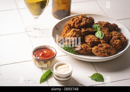 Ali di pollo in stile bufalo servite con birra fredda su sfondo bianco Foto Stock