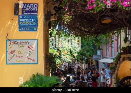 Chania, Creta, Grecia - 22 giugno 2025: I visitatori esplorano una vivace strada di Chania, Creta, adornata da fiori e cartelli vivaci. Foto Stock