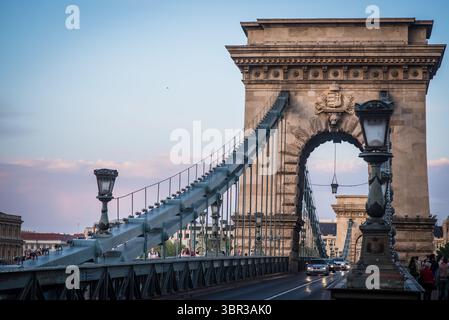 Vista del Ponte delle catene di Szechenyi che si estende attraverso il Danubio sotto un morbido cielo mattutino, le sue colonne di pietra che gettano le ombre, Budapest, Ungheria centrale, Ungheria. Foto Stock